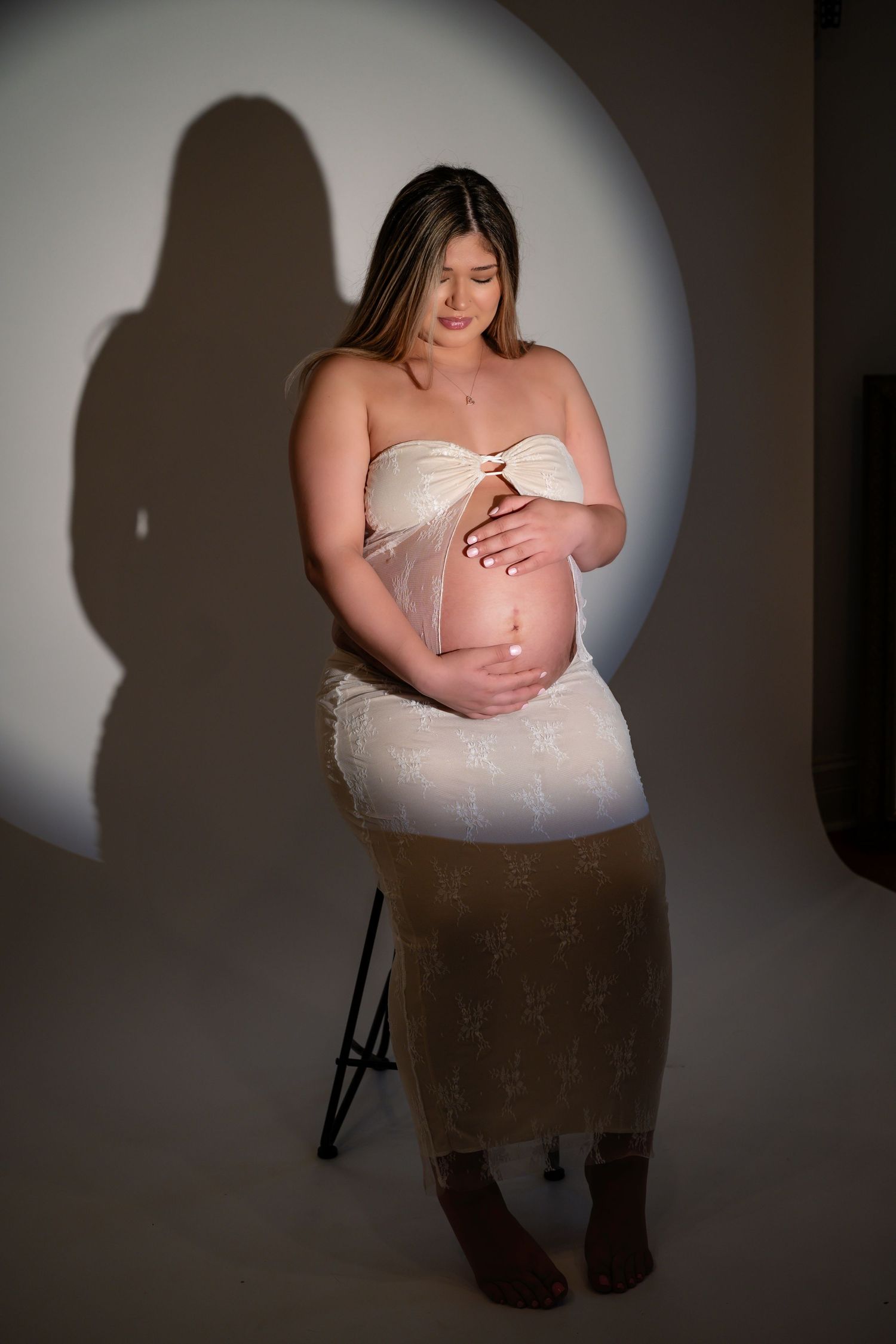 Artistic portrait against dramatic lighting in a white dress with shadow effects.