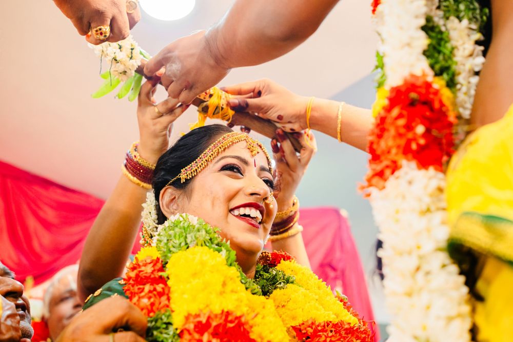 Joyful pre-wedding ceremony with flower garlands and traditional yellow turmeric applications.