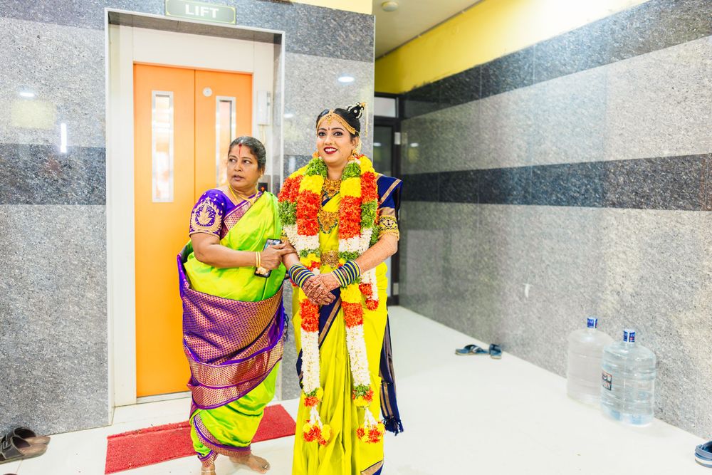 Women wearing vibrant traditional Indian saris stand near an orange door in a modern hallway.