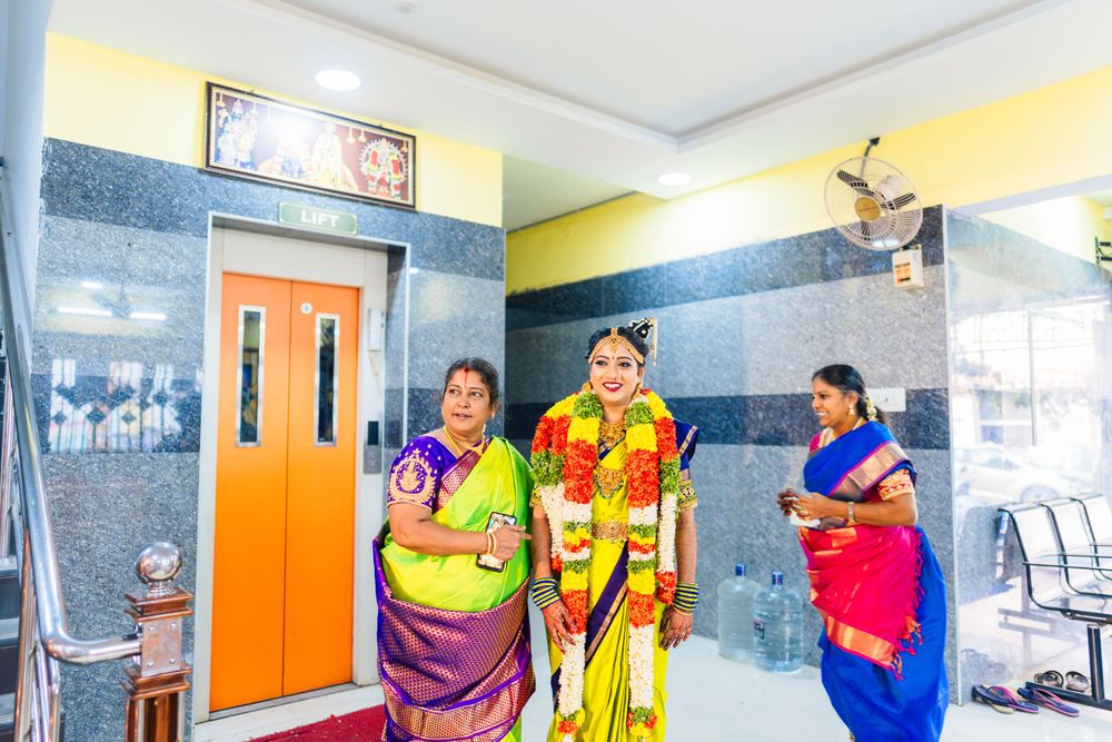 Group in colorful traditional Indian attire gathered in a hallway with striped walls and orange door.