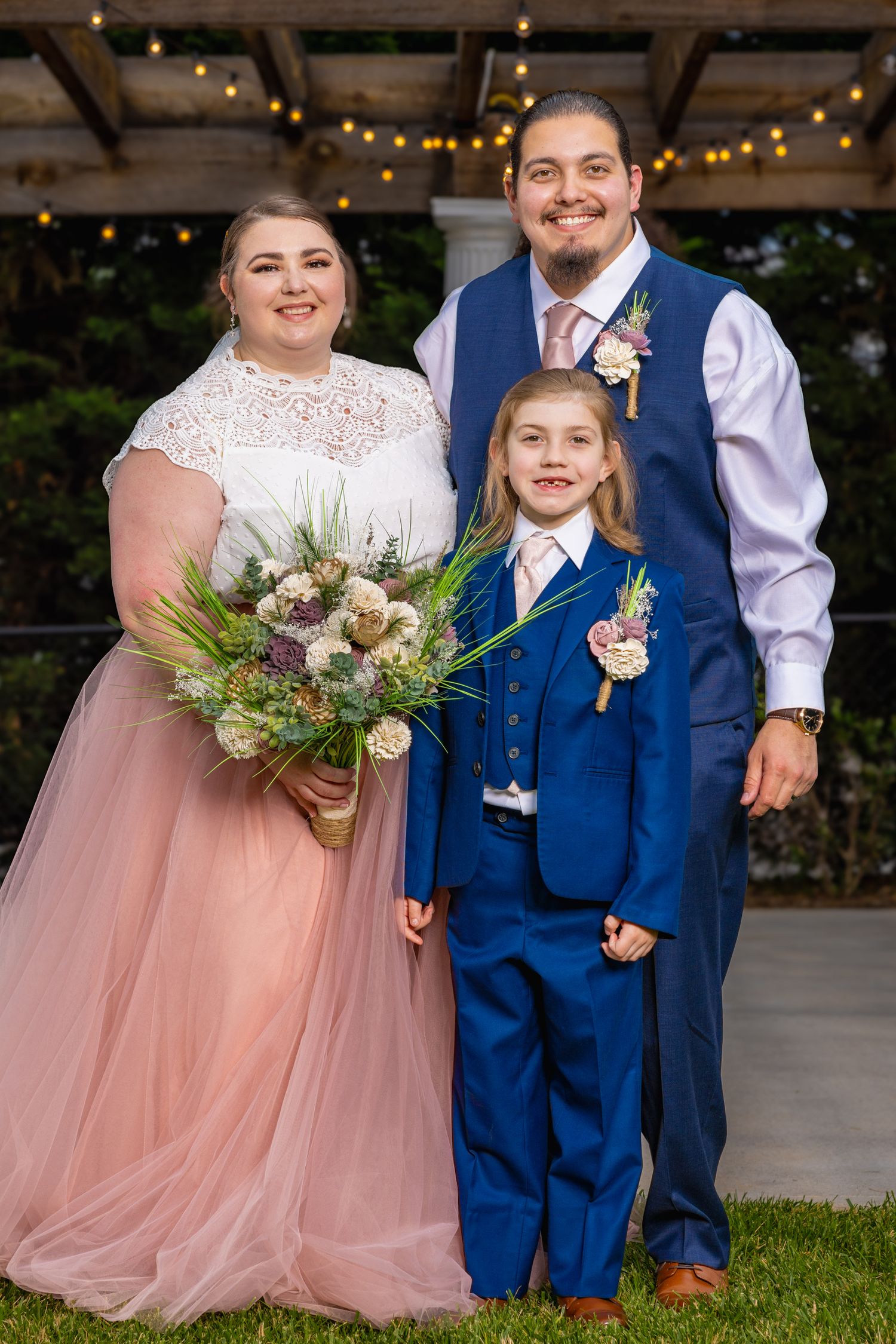 A couple posing for a portrait with their son at their wedding