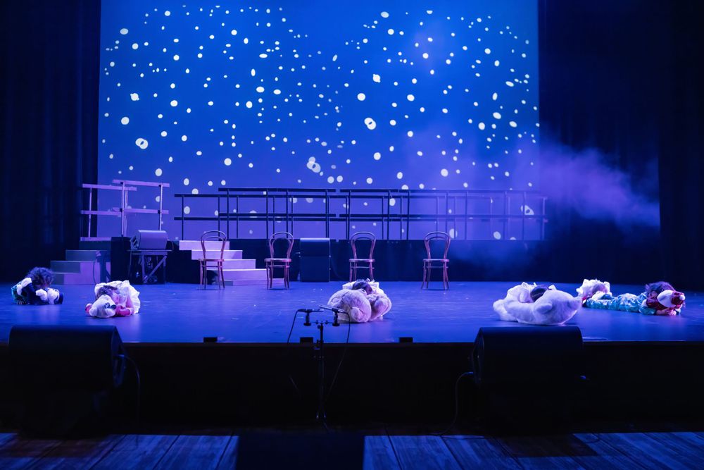 Theater stage with starry backdrop features performers in a dreamy nighttime scene.