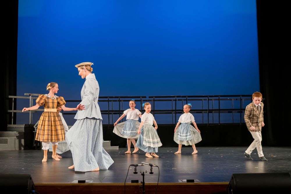 Stage performance featuring period costumes with vintage-style dresses and formal attire.