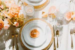 A table setting with vibrant orange flowers is hit by the natural sunlight.