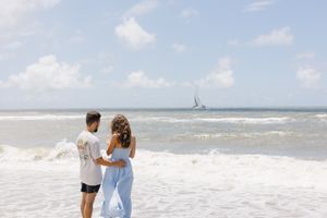 A woman admires her new diamond ring after being proposed to on the beach.