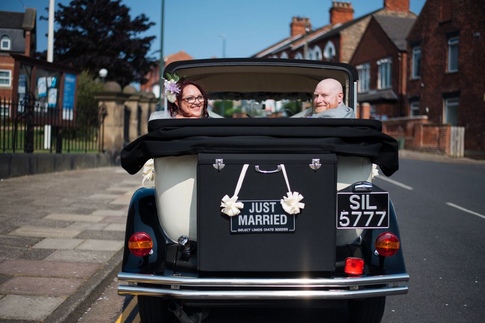Classic vintage wedding car decorated with Just Married sign viewed from behind.