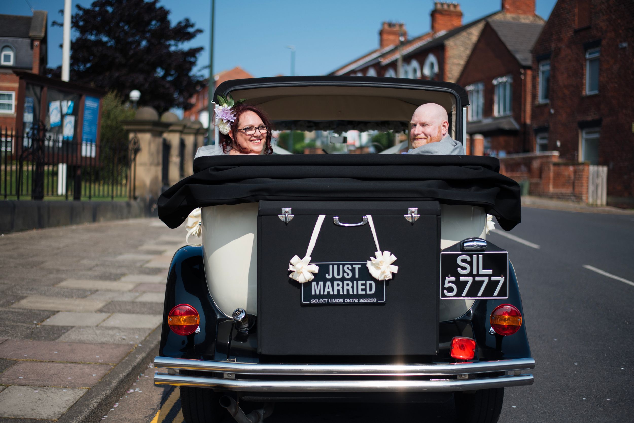 Classic vintage wedding car decorated with Just Married sign viewed from behind.