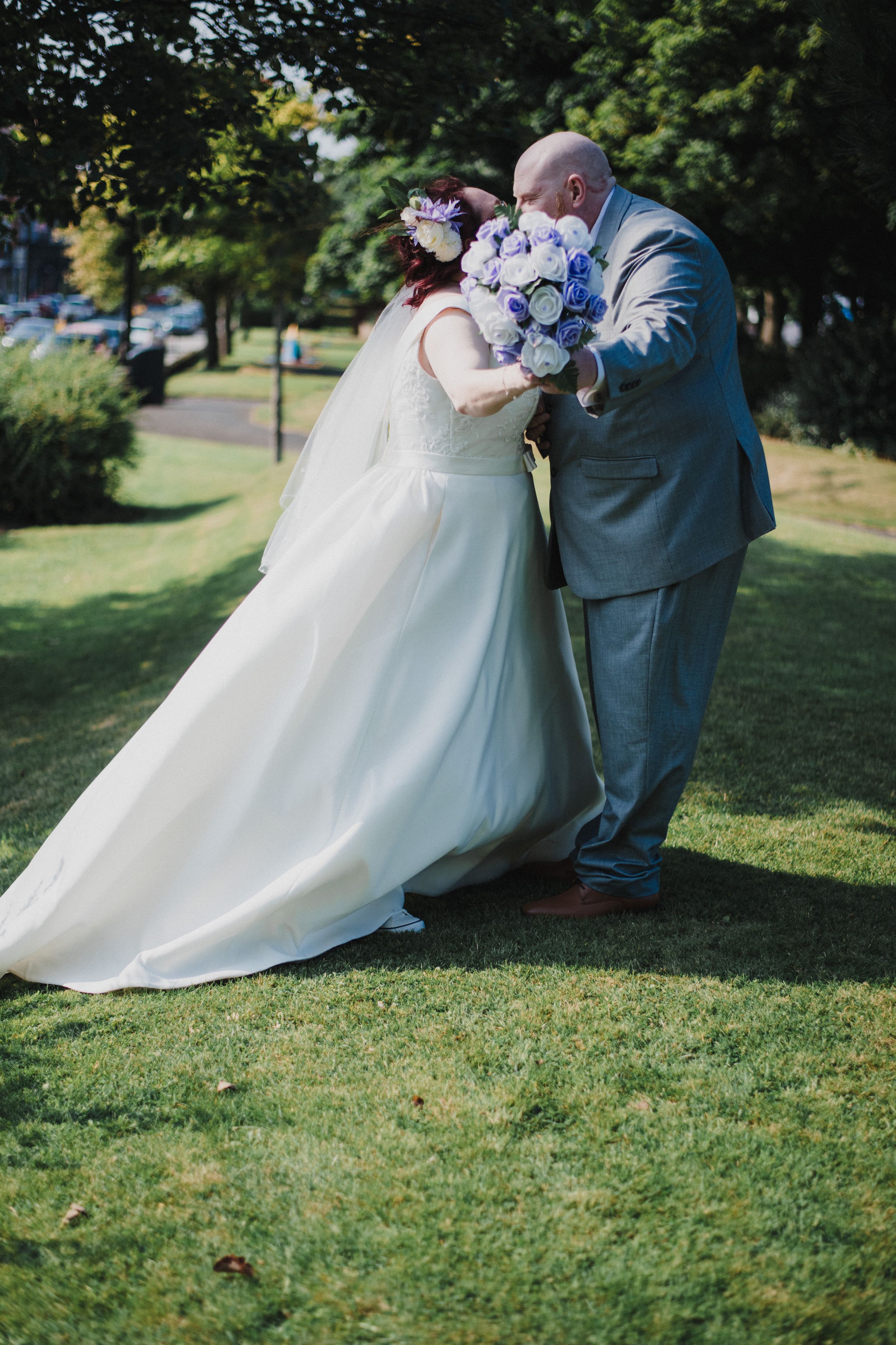 Romantic garden wedding portrait with flowing white dress and blue flowers.