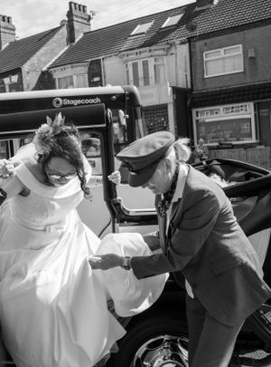 Black and white photo of bride getting assistance boarding vintage transport.