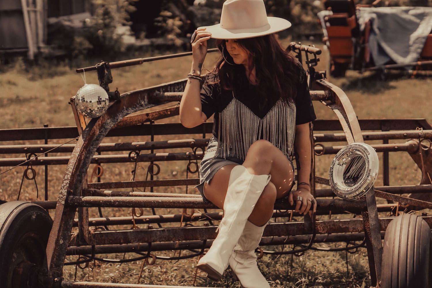 A rustic western scene with cowboy boots and fringe against a wooden fence.