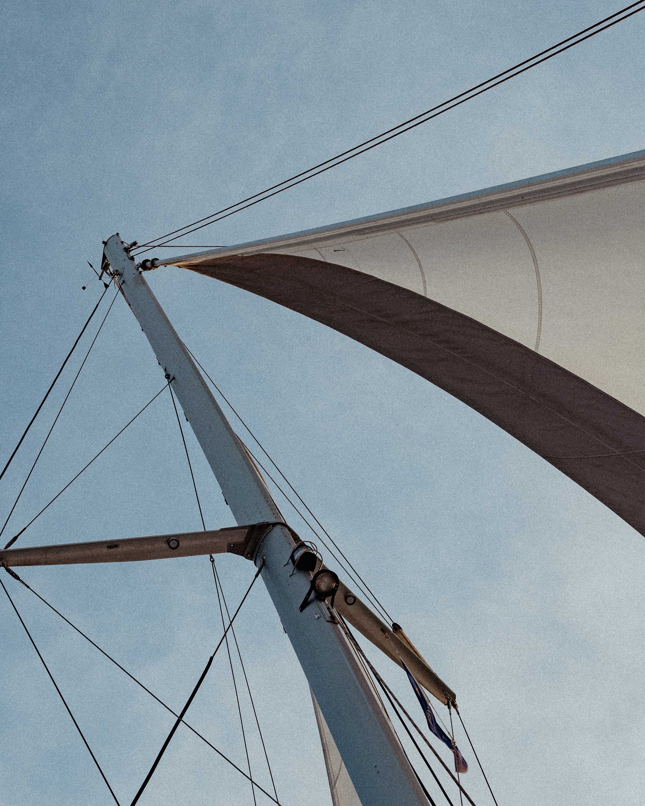 Detail of a white sailboat mast and rigging against a blue sky.