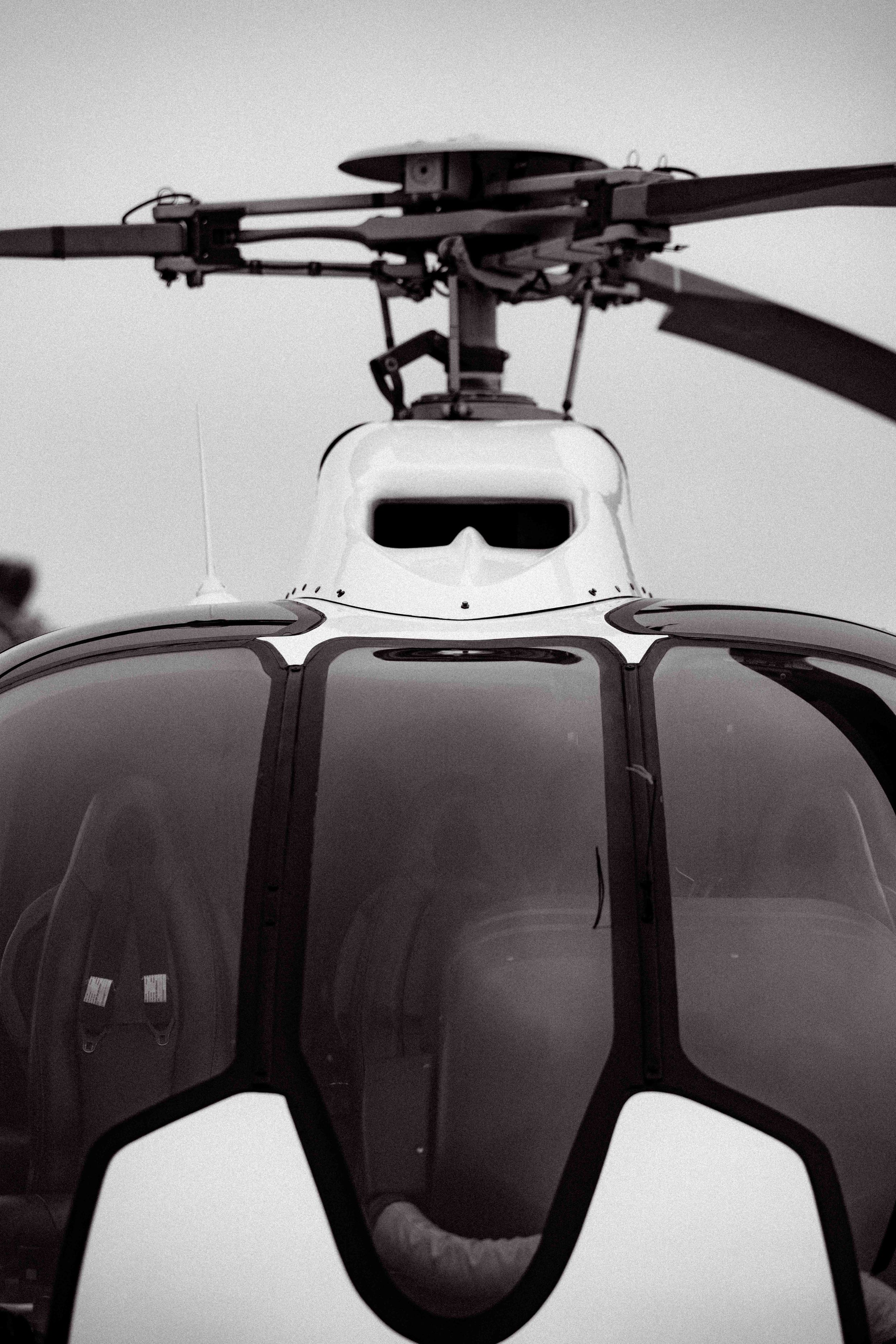 Close-up black and white detail of a helicopter rotor system and cockpit.