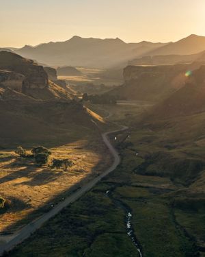 Winding mountain road cutting through a valley at golden hour with dramatic shadows.