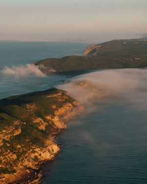 Coastal cliffs with low-lying fog rolling in during golden sunset.