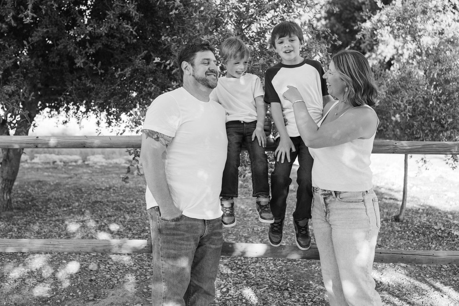 A black and white photo of two adults with a child outdoors in a casual setting.