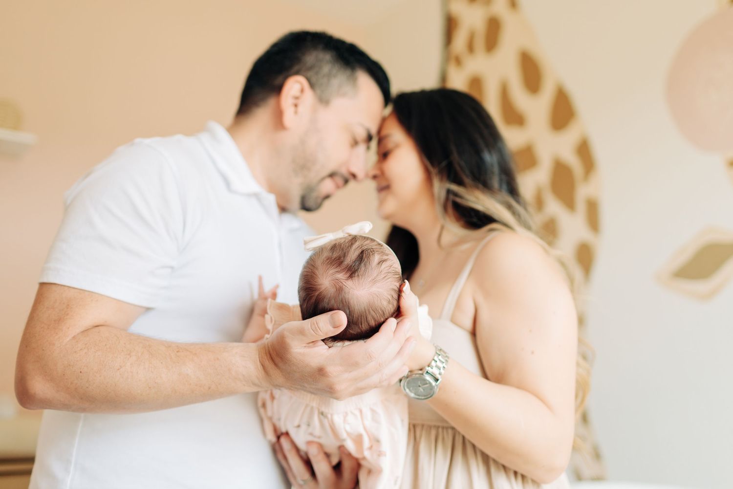 Intimate moment during Orlando newborn photo session of mom and dad holding the baby and touching their foreheads