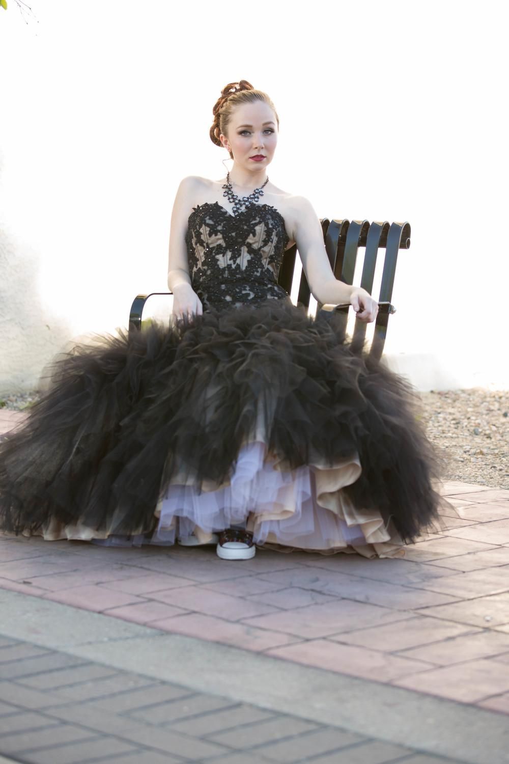 Dramatic black tulle gown with lace bodice photographed outdoors on patio furniture.