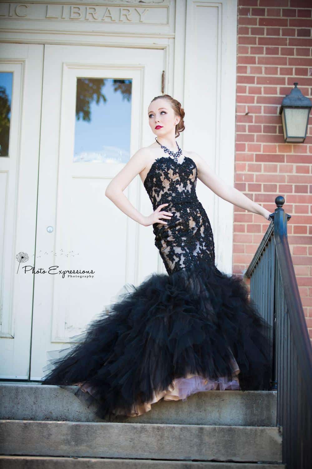 Fashion photo on library steps featuring black mermaid gown with tulle skirt.