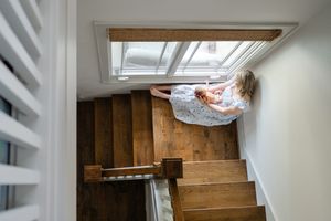 mother sits on stairs with newborn in lap for Oklahoma City newborn photographer