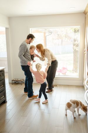 A family shares a tender moment together in their bright modern home with hardwood floors while their dog watches nearby in OKC