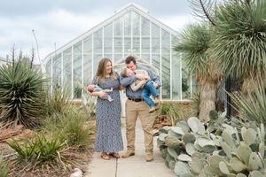 A family stands together on a garden path in front of Will Rogers gardens in Oklahoma City for newborn photography