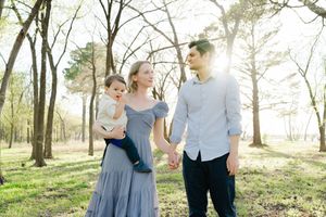 A family walks together through a sunlit forest on a spring afternoon for family photographer in Oklahoma City, OK