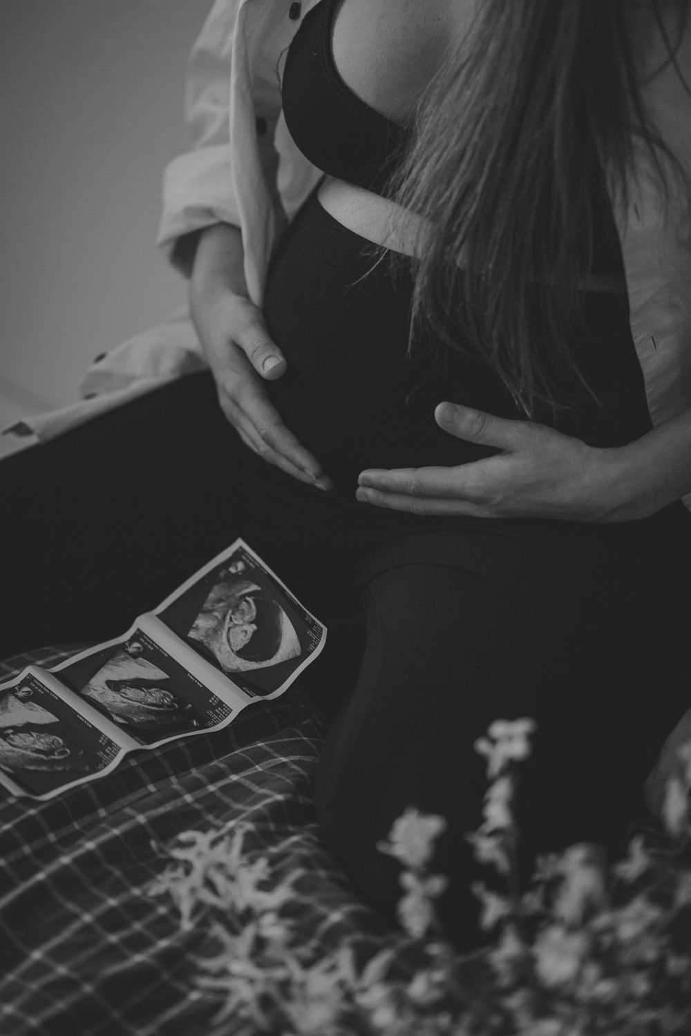 Black and white photo of pregnant belly with ultrasound images.