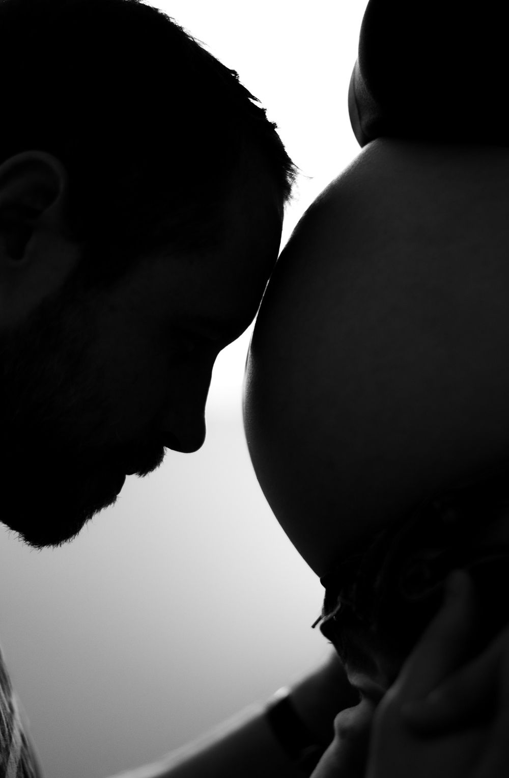 Silhouette of expectant parents sharing a tender moment with pregnant belly.