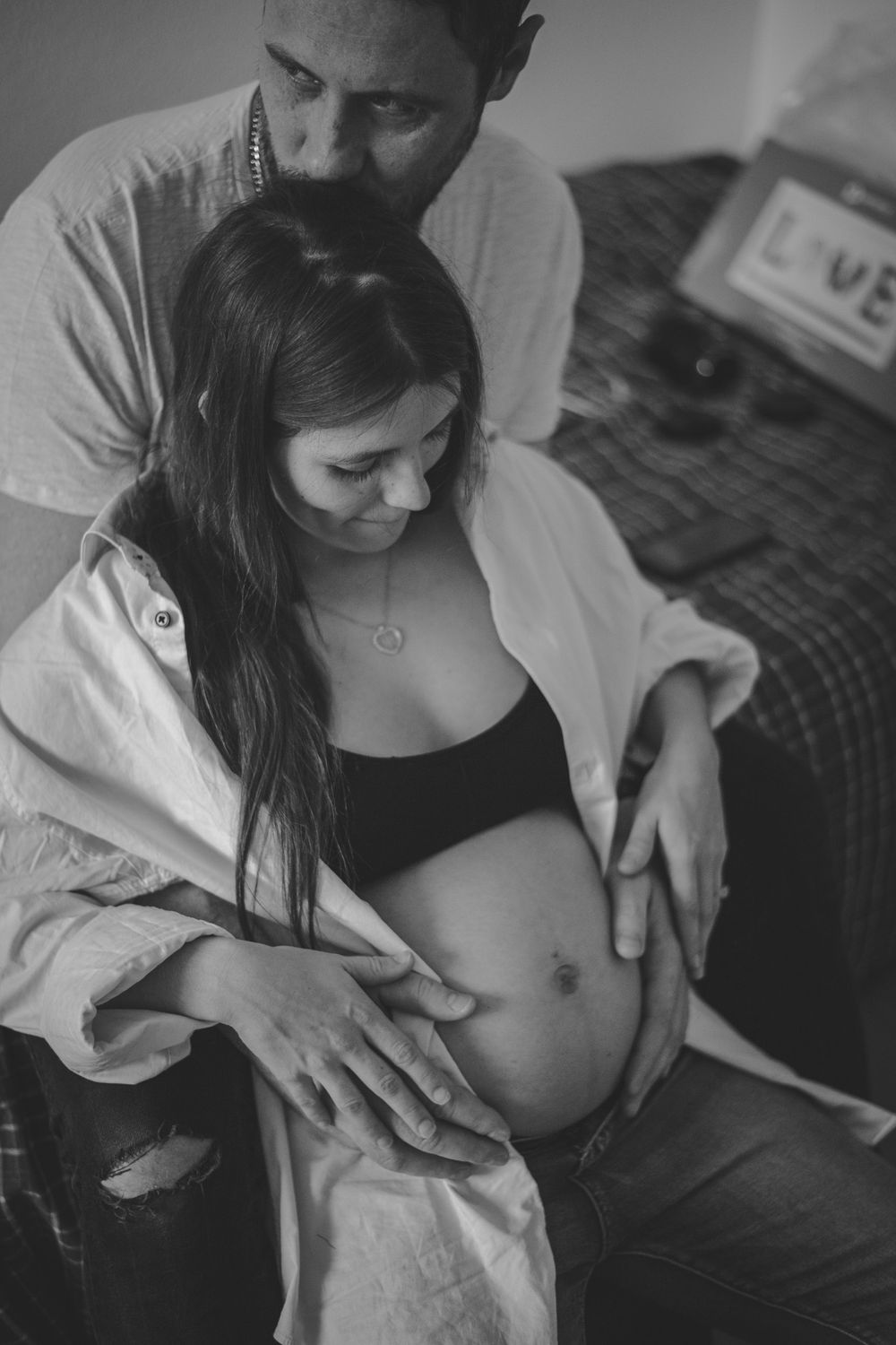 Black and white intimate maternity photo showing couple embracing pregnancy.