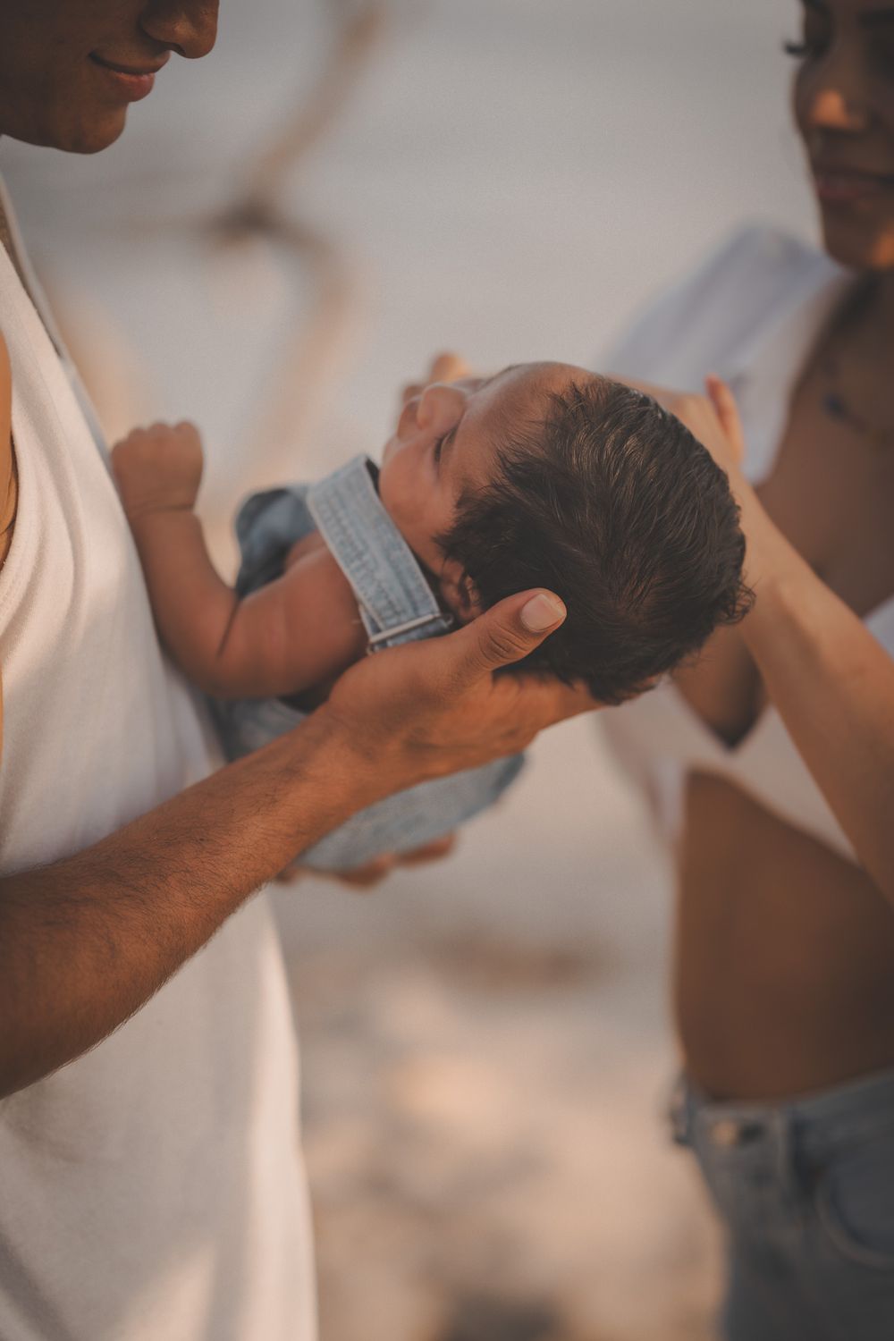 A tender moment as parents hold their newborn baby in soft natural light.