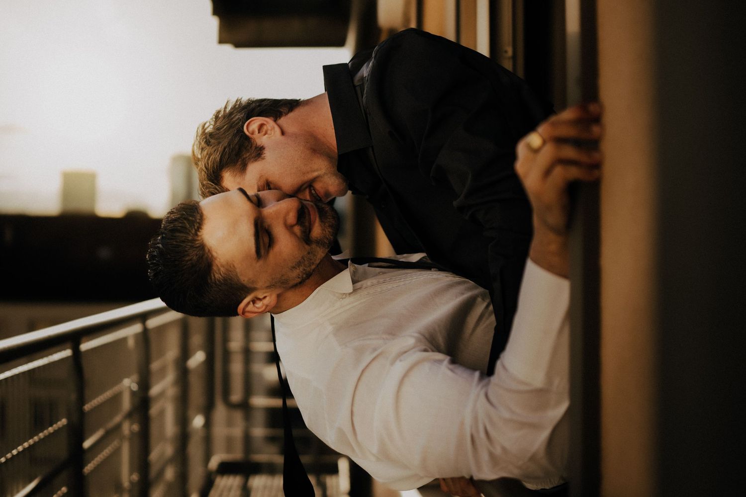 Couple embracing on a balcony with warm moody lighting.