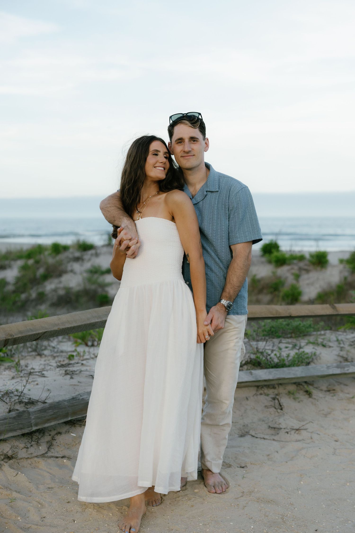 Intimate moment between couple in white attire against green garden backdrop.
