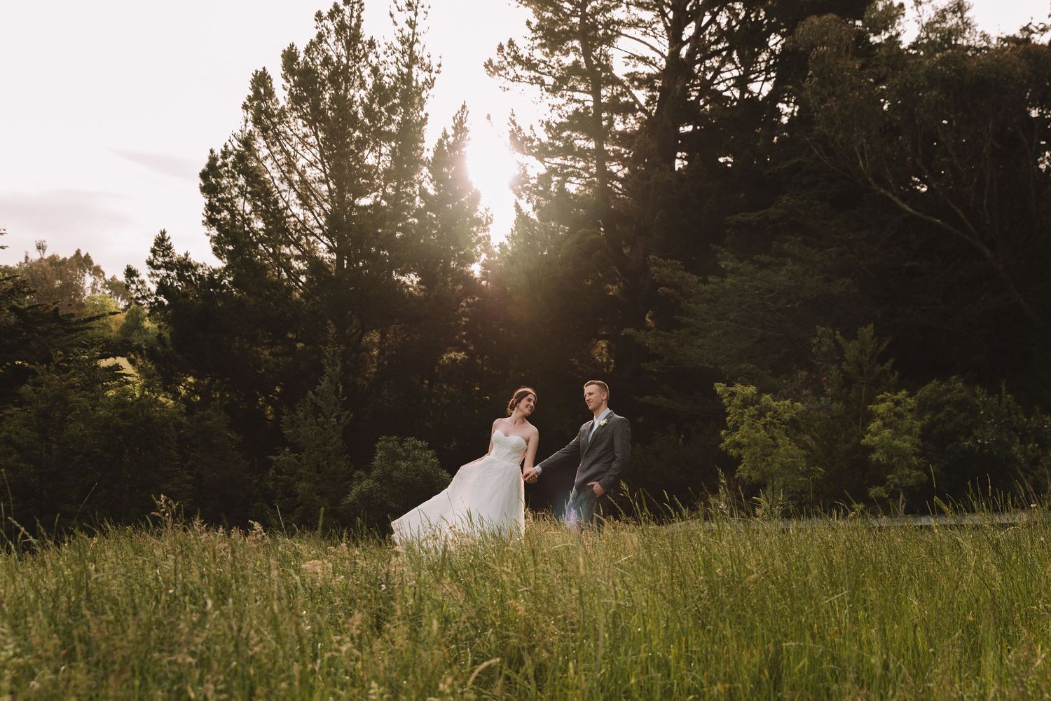 Sunset wedding portrait silhouette in field with trees and golden light.