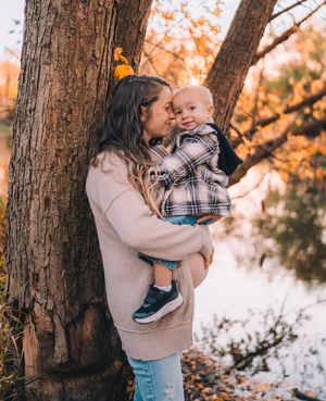 Parent and child share tender moments in a snowy winter forest setting during golden hour.
