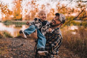 A joyful moment shared between two people on an autumn day with golden foliage in the background.