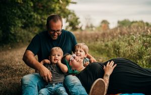 A family enjoys a playful outdoor photoshoot in a natural setting during golden hour.