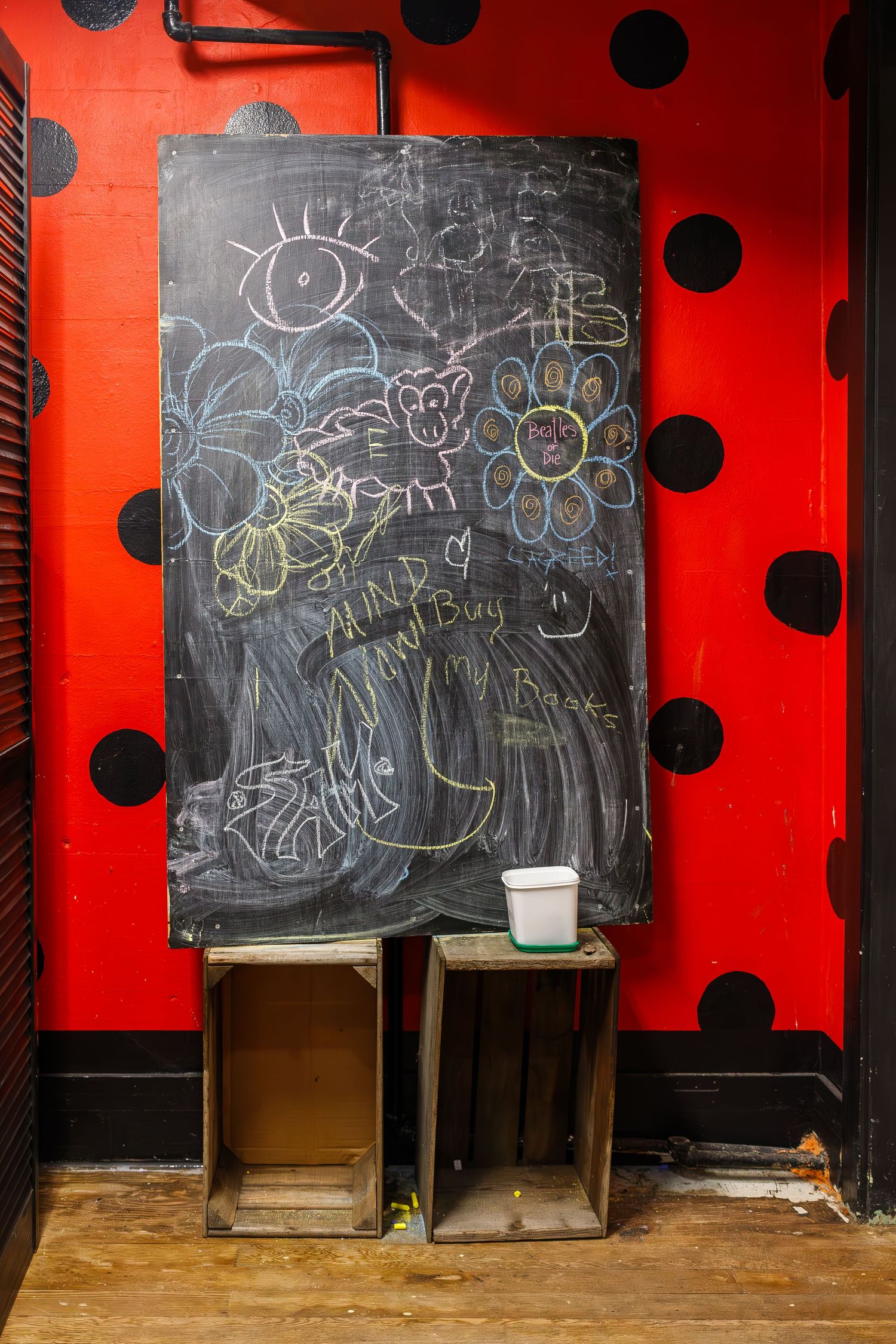 Chalkboard with whimsical drawings mounted on red polka dot wall.