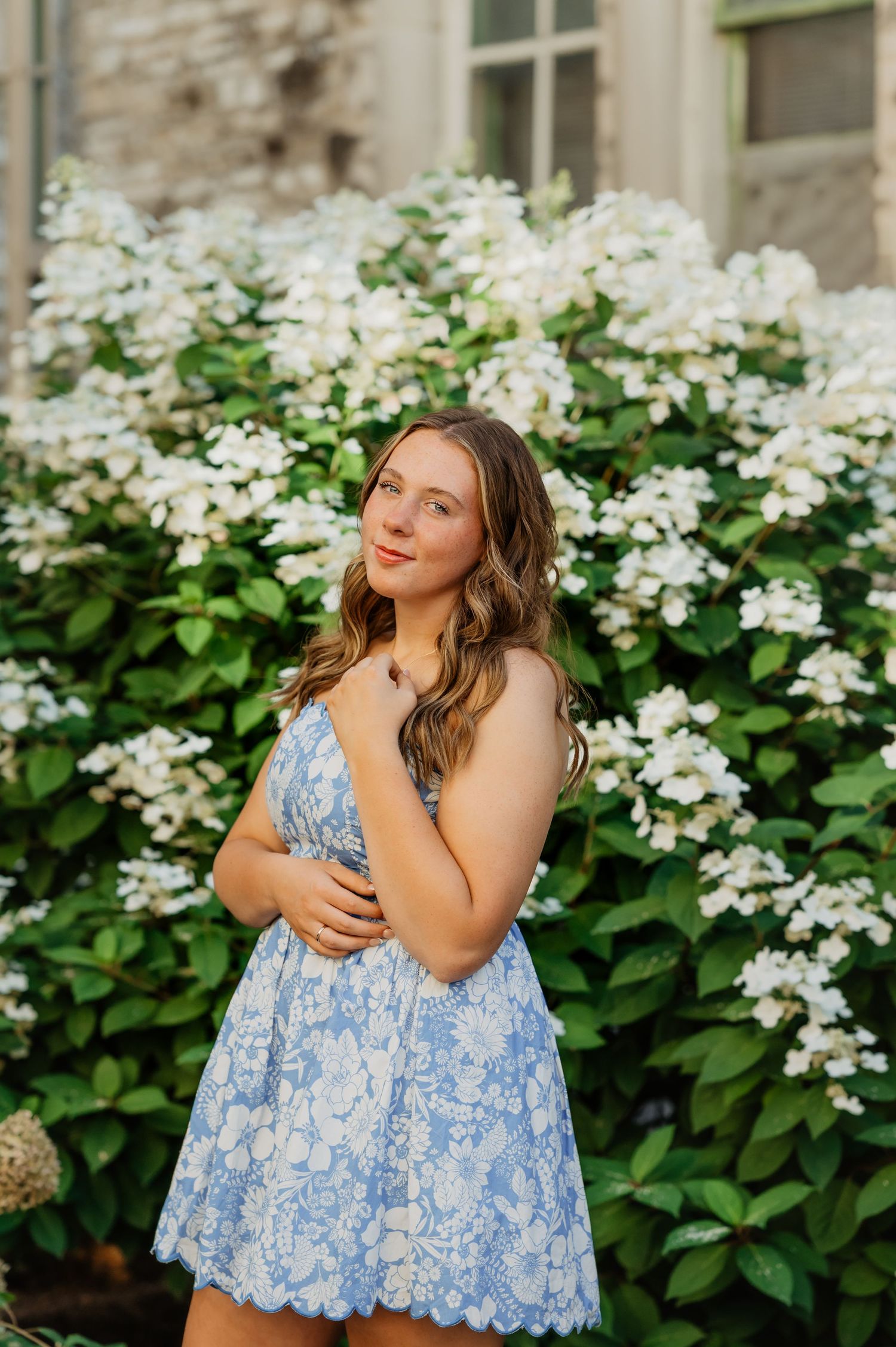 Portrait by distressed blue brick wall with person in casual attire sitting on ground.