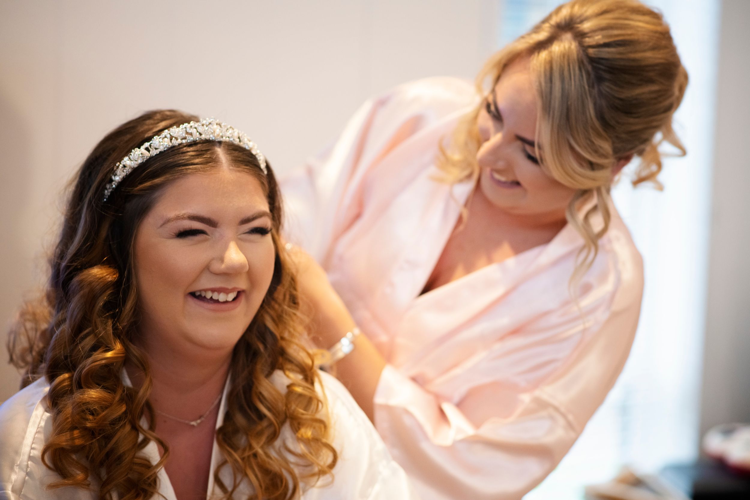 A wedding preparation scene with styling taking place in a pink robe.