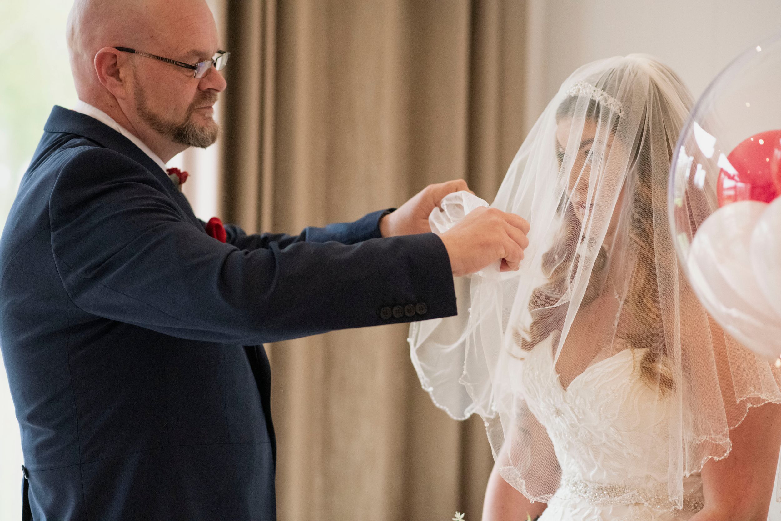 A tender moment of adjusting a wedding veil during the ceremony preparations.