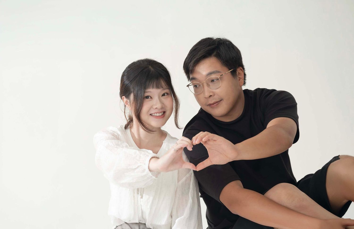 Couple making heart shape with hands in studio setting. in Melbourne photography studio