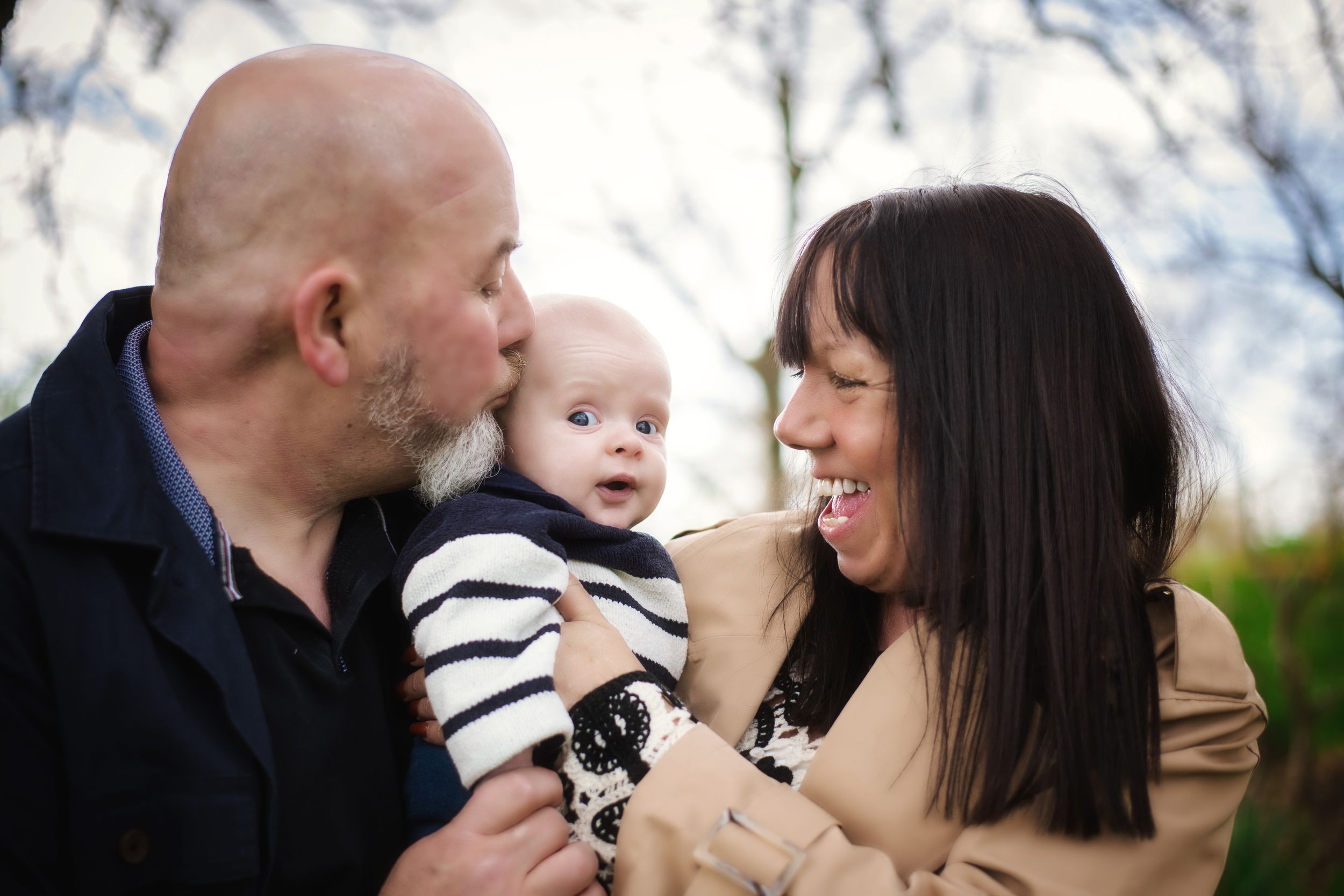 Outdoor family portrait with baby captured during golden hour.