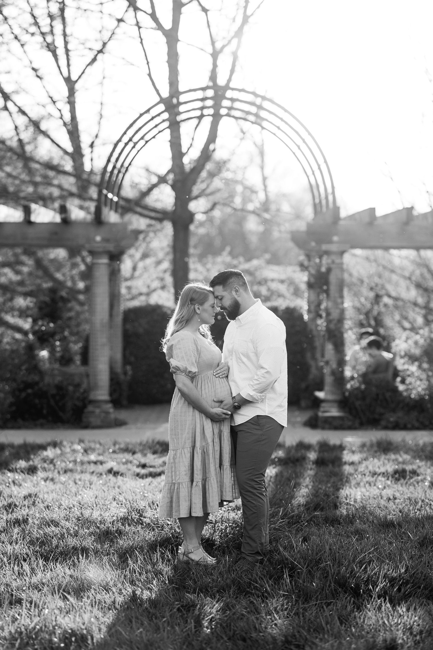 Black and white portrait of couple under garden arch in spring setting.