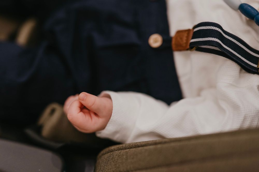 Close-up of a baby's arm in formal white and navy clothing.
