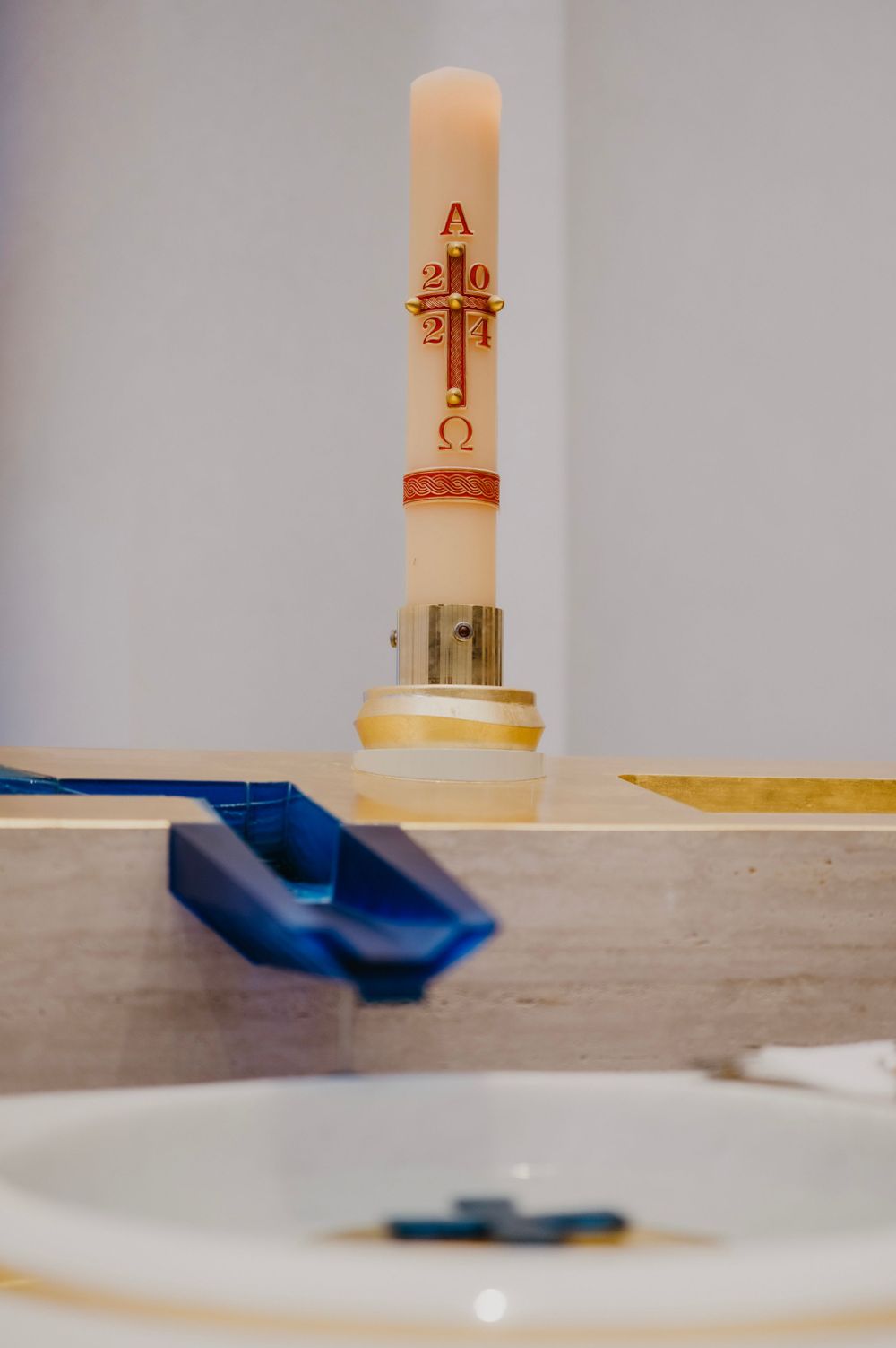 Ceremonial candle with ornate cross design in gold and cream colors.
