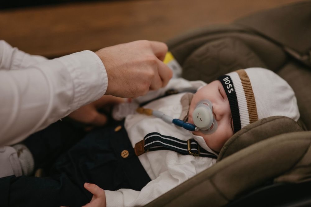 Baby in formal attire being cared for during a special event.