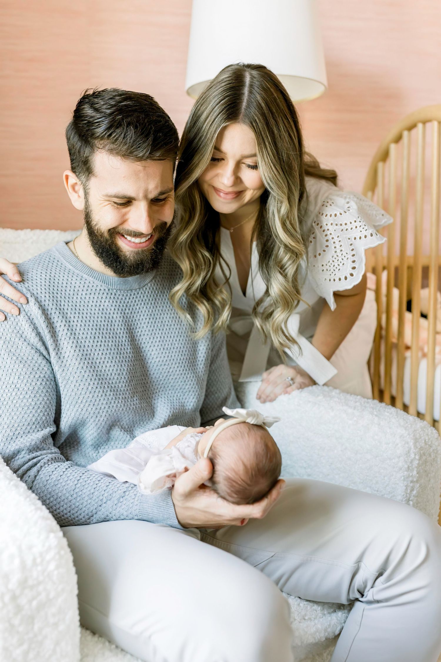 Parents share joyful moment with newborn baby while sitting in nursery chair.