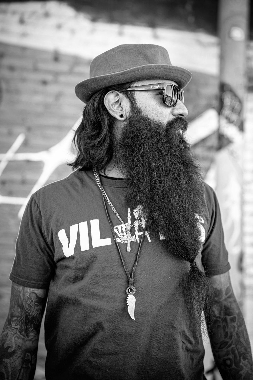 Bearded man in black t-shirt and hat shown in artistic black and white portrait series.
