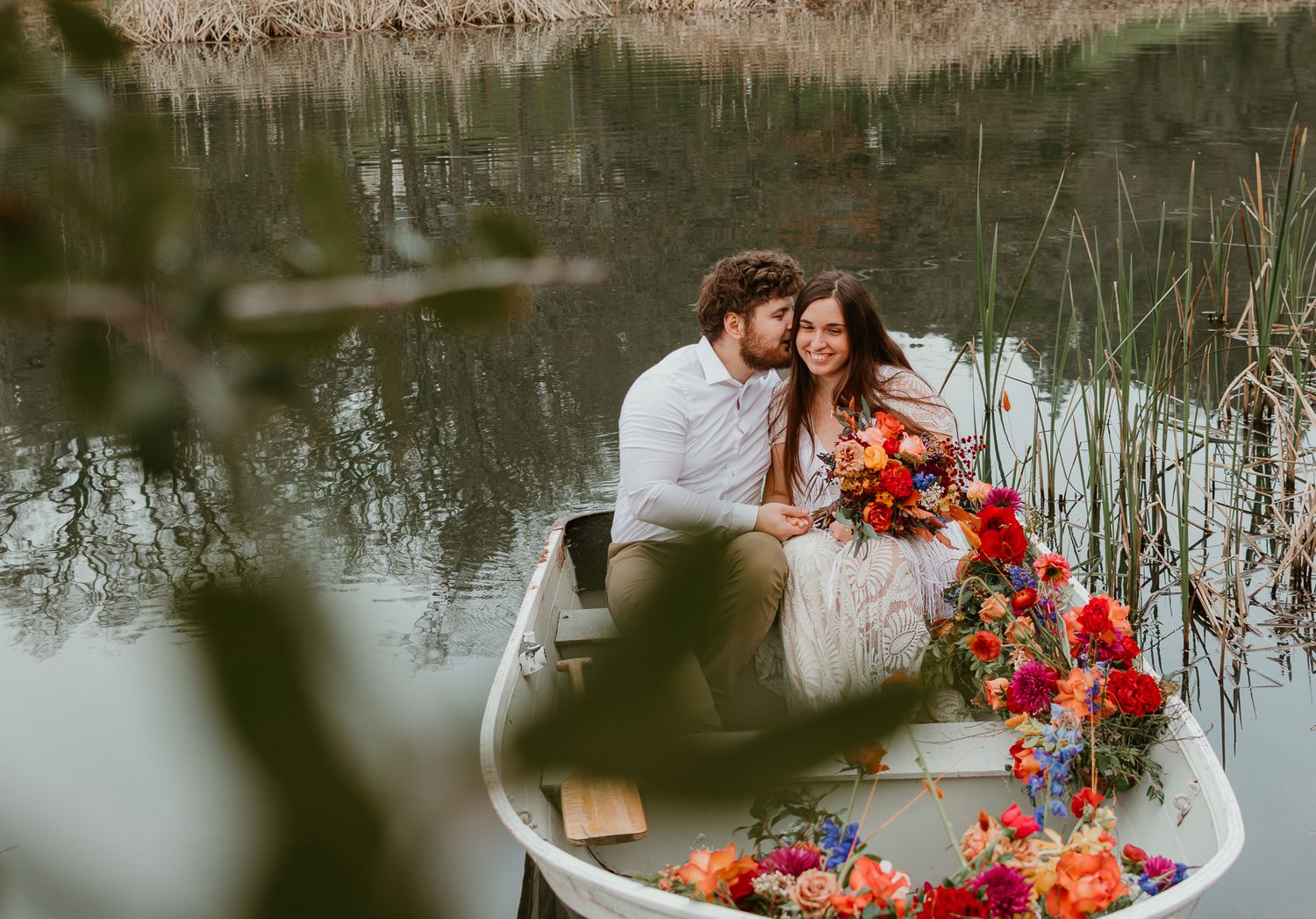 A romantic boat scene decorated with vibrant red and pink flowers on a peaceful lake.