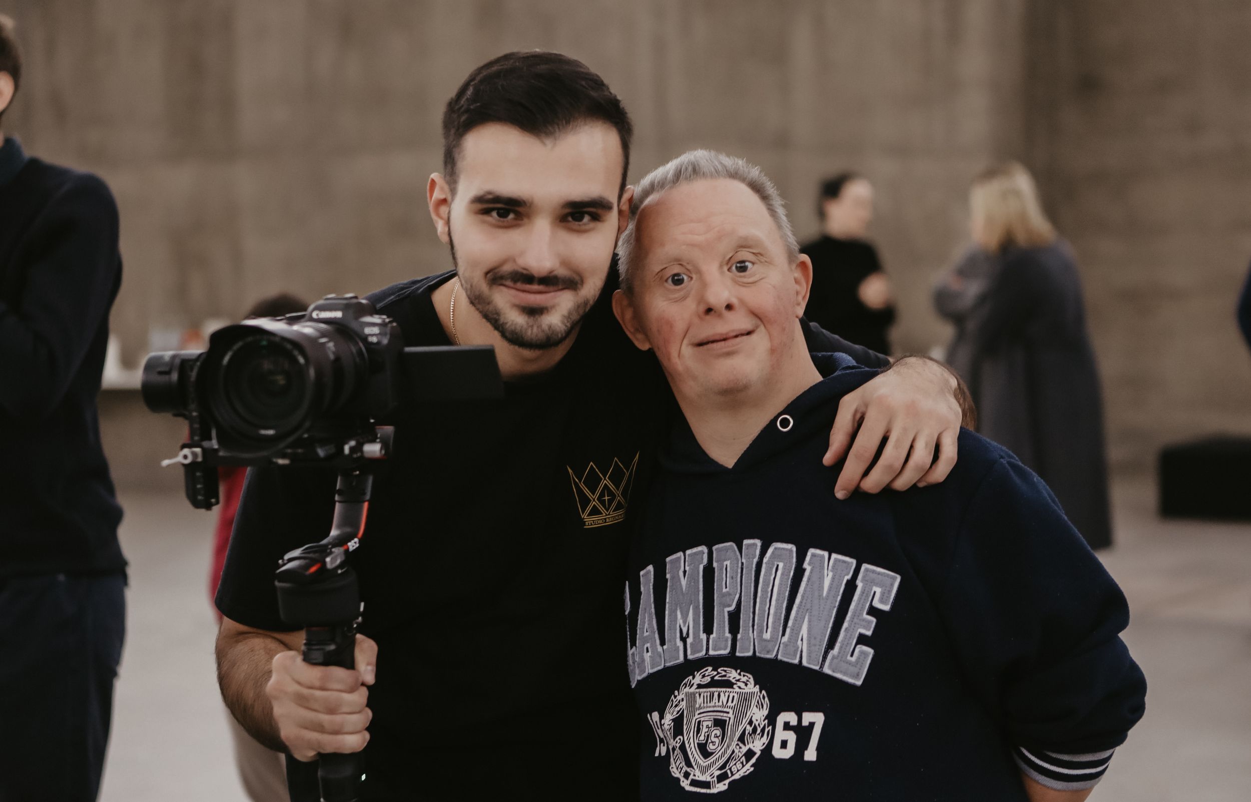 Two people with camera equipment smile together during a photo shoot.